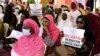 Seorang perempuan memegang poster yang bertuliskan "LGBT adalah ancaman bagi kemanusiaan" dalam sebuah aksi protes menentang homoseksualitas yang dilakukan oleh kelompok agama di alun-alun Obelisque di Dakar, Senegal, pada 23 Mei, 2021. (Foto: AFP/Seyllou)