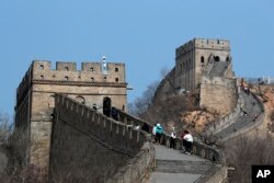 Pengunjung yang mengenakan masker pelindung berjalan di Tembok Besar China di Badaling di China, Selasa, 24 Maret 2020. (Foto: AP)