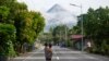 Seorang perempuan yang menggendong anaknya tampak mengamati gunung berapi Mayon di Legazpi, provinsi Albay, Filipina, pada 13 Juni 2023. (Foto: AP/Aaron Favila)