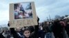 Seorang remaja memegang plakat bergambar Presiden Prancis Emmanuel Macron duduk di tong sampah bertuliskan, "raja sampah" saat protes di Paris, Jumat, 17 Maret 2023. (Foto: AP)