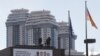 Para pekerja tampak berdiri di atas atap dari kantor kedutaan Jerman di Moskow, Rusia, saat berusaha membetulkan spanduk yang terpasang di gedung kantor tersbeut pada 29 Maret 2018. (Foto: Reuters/Maxim Shemetov)