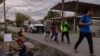 Una familia migrante de Venezuela pasa junto a un hombre comiendo en un puesto al borde de la carretera tras haber sido disuadida por las autoridades locales de cruzar el río Grande hacia Eagle Pass, en Texas, desde Piedras Negras, Coahuila, México el 7 de octubre. [REUTERS]