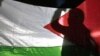 Seorang anak laki-laki mengibarkan bendera Palestina saat unjuk rasa di luar kantor PBB di Amman. (Foto: AFP)