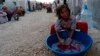 A Kurdish refugee girl from the Syrian town of Kobani washes in front of their family tent in a camp near the Syria-Turkey border in the southeastern town of Suruc, Turkey, Oct. 10, 2014.
