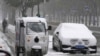 Seorang petugas pengantaran dengan motornya bergerak melewati mobil yang berselimut salju di di Beijing, China, pada 7 November 2021. (Foto: AP/Ng Han Guan)
