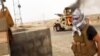 A militant standing in front of a burning Iraqi Army Humvee in Tikrit, Iraq, June 12, 2014. 