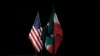 Seorang petugas membereskan bendera Iran yang terpasang di samping bendera AS dari atas panggung setelah pembicaraan nuklir Iran selesai dilaksanakan di Wina, Austria, pada 14 Juli 2015. (AP/Carlos Barria)