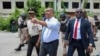 Haitian Prime Minister Garry Conille points as he walks with Police Chief Normil Rameau, left, while surrounded by security during their visit to the General Hospital in Port-au-Prince, Haiti, July 9, 2024. 