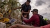 Una niña migrante venezolana es asistida por compatriotas mientras intentan pasar entre alambres de púas colocados a lo largo de las orillas del río Grande, en Eagle Pass, EEUU, el 6 de octubre de 2023.