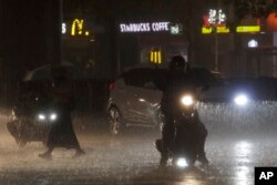 Sejumlah pengendara motor dan pejalan kaki di tengah guyuran hujan lebat akibat Topan Haikui yang melanda Taipei, Taiwan, Sabtu, 2 September 2023. (Foto: Chiang Ying-ying/AP Photo)