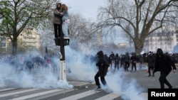 Polisi antihuru-hara di Paris menembakkan gas air mata ke arah pengunjuk rasa dalam aksi protes hari Selasa (28/3). 