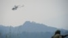 Helikopter milik PBB terbang melintasi Taman Nasional Virunga ketika dua tentara dari pasukan bersenjata Republik Demokratik Kongo berjaga di dekat Desa Kibumba, Provinsi Kivu Utara, pada 11 Juli 2012. (Foto: AFP/Phil Moore)