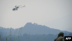 Helikopter milik PBB terbang melintasi Taman Nasional Virunga ketika dua tentara dari pasukan bersenjata Republik Demokratik Kongo berjaga di dekat Desa Kibumba, Provinsi Kivu Utara, pada 11 Juli 2012. (Foto: AFP/Phil Moore)