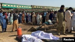 Orang-orang berkumpul di dekat mayat di lokasi tabrakan antara dua kereta di Ghotki, Pakistan 7 Juni 2021. (Foto: Reuters)