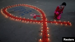 Seorang perempuan tampak menyalakan lilin dalam peringatan Hari AIDS sedunia di Kolkata, India, pada 1 Desember 2021. (Foto: Reuters/Rupak De Chowdhuri)